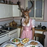 amber_eyes anthro antlers big_breasts black_lips black_nose breasts chair cleavage clothed clothing cutlery detailed_background dirndl dress eyebrows eyelashes female food fork fully_clothed furniture happy horn inner_ear_fluff inside kitchen kitchen_utensils lips long_eyelashes looking_at_viewer open_mouth open_smile photorealism pink_clothing plant plate potato realistic salad sink smile solo standing table teapot tile tile_wall tongue tools tuft vegetable vintage wall_(structure) window silvicultor cervid mammal hi_res